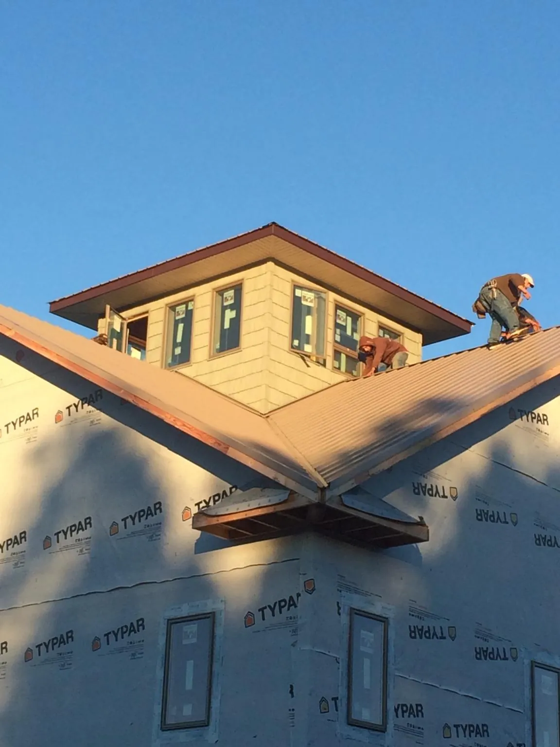 Roofers working around a rooftop cupola on a new metal roof at sunset — Roof Waterproofing in Woodbridge by Roofing Brothers